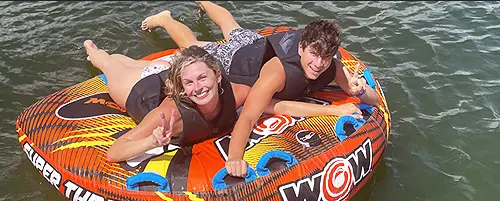 Two people tubing behind a wakeboard boat on Percy Priest Lake in Nashville, Tennessee.